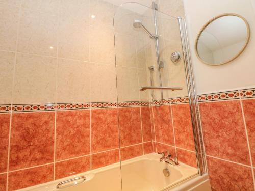 a shower stall with a tub and a mirror at 4 Alma Road in Buxton