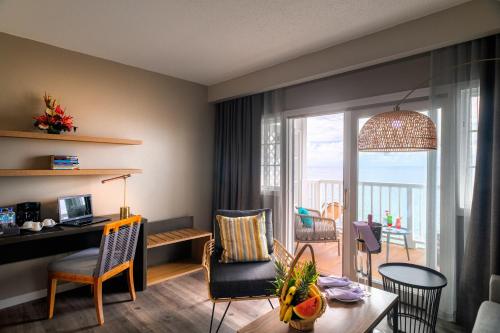 a living room with a desk and a living room with a balcony at Fort Young Hotel in Roseau