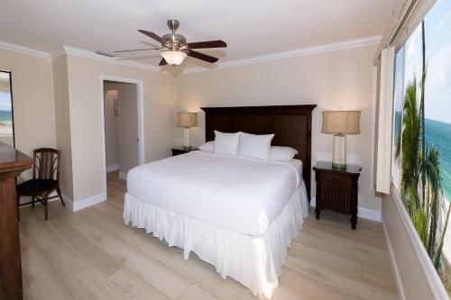 a bedroom with a white bed and a ceiling fan at Cedar Cove Resort & Cottages in Holmes Beach