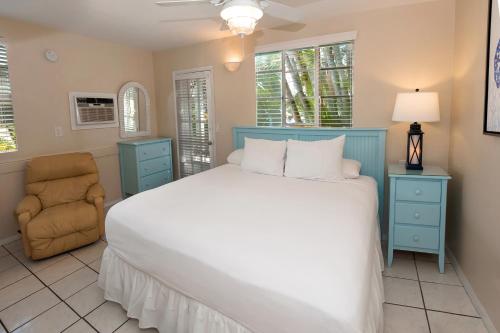 a bedroom with a large bed and a chair at Cedar Cove Resort & Cottages in Holmes Beach