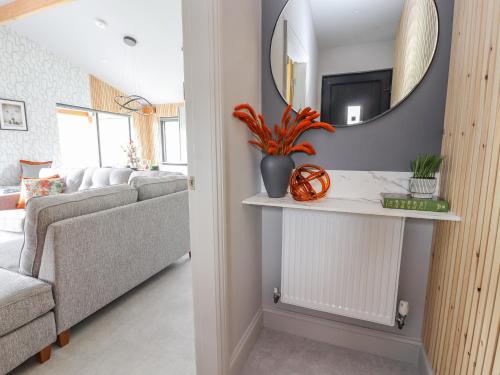 a living room with a mirror and a couch at Pool View in Meifod