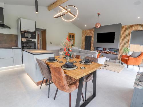 a kitchen and living room with a wooden table and chairs at Pool View in Meifod