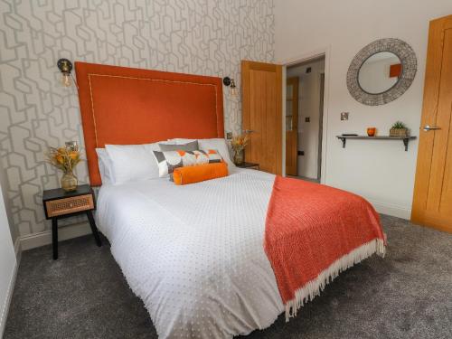 a bedroom with a bed with an orange and white comforter at Pool View in Meifod