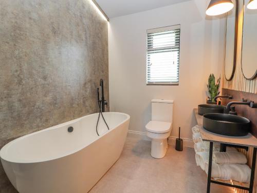 a bathroom with a tub and a toilet and a sink at Pool View in Meifod