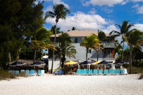a resort on the beach with chairs and umbrellas at Cedar Cove Resort & Cottages in Holmes Beach