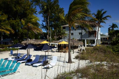 a group of chairs and umbrellas on a beach at Cedar Cove Resort & Cottages in Holmes Beach