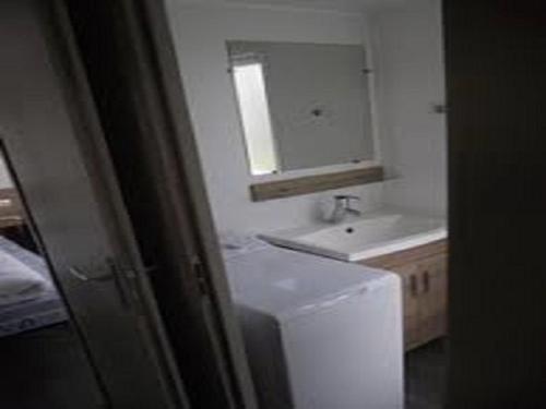 La salle de bains est pourvue d'un lavabo, de toilettes et d'un miroir. dans l'établissement MOBIL HOME CAMPING LES SABLES DU MIDI, à Valras-Plage