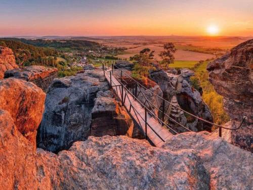 a suspension bridge on a rocky mountain at sunset at Apartman Hruba Skala in Hrubá Skála