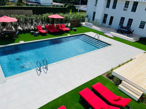 a swimming pool with red chairs and umbrellas at Seven - a boutique B&B on Shelter Island in Shelter Island
