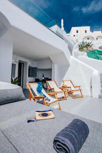 a room with a bed and chairs and a table at Virginia's Cave Villas in Oia