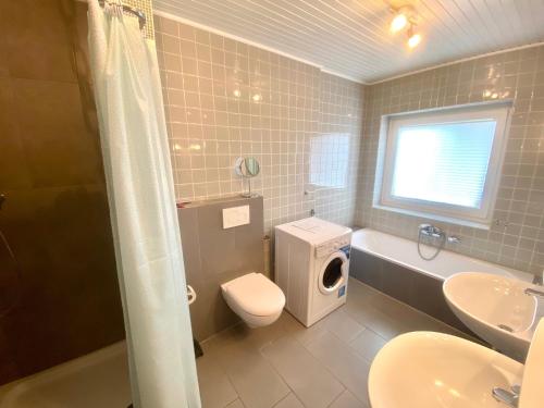 een badkamer met een toilet, een wastafel en een wasmachine bij 8001 - Sol y Mar in Dahme