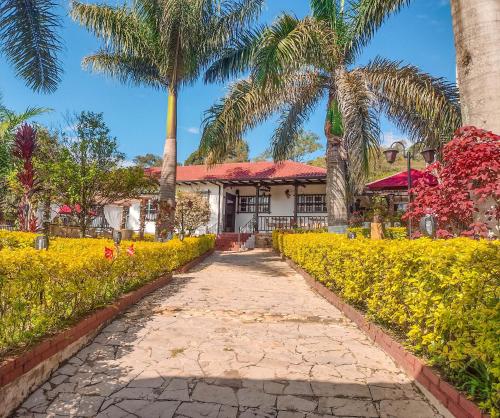 a walkway in front of a building with palm trees at Hotel Casona del Virrey in Moniquirá