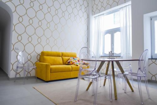 a dining room with a yellow couch and a table and chairs at Corso Vittorio Elegant Suites Lipari in Lipari