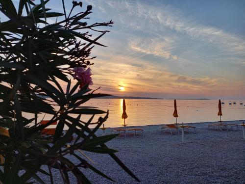 a sunset on a beach with chairs and umbrellas at Villa Claudia in Fažana