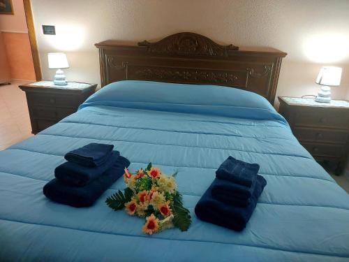 a bed with two blue towels and flowers on it at Welcome to La Panoramica in Montauro