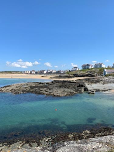 a body of water with a beach in the background at Anglesey Coastal Cottage 200 metres from Beach, Dog and Family Friendly in Trearddur