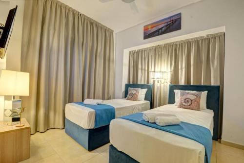 a hotel room with two beds and a lamp at SunnyVillas: 4BR Villa☆Private Pool + Jacuzzi - Villa Amelie in Protaras