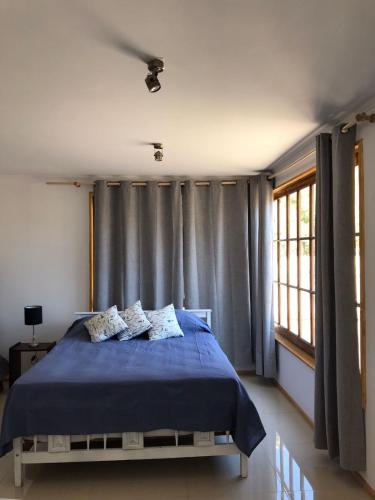um quarto com uma cama azul e uma janela em Cabaña de 1 ambiente para hasta 4 personas em Putaendo