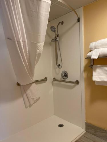 cabina de ducha con cortina de ducha y toallas en Baymont by Wyndham Dunmore en Dunmore
