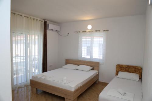 two beds in a room with white walls and windows at Apartments Armini in Ulcinj