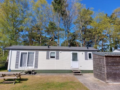 a white house with a picnic table and a bench at Modern en chic chalet tot 4 personen op de Veluwe Recreatiepark De Oude Driest - All inclusive in Putten