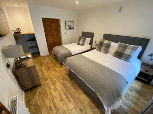 a bedroom with two beds and a wooden floor at Ravenscraig Guest House in Aviemore