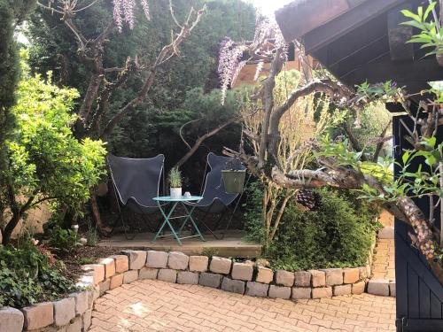 a patio with two chairs and a table in a garden at Le jardin de félicie in Trévoux