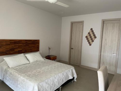 a white bedroom with a bed and a chair at Cartagena, gran experiencia frente al mar a 20 minutos del centro histórico y 13 minutos del aeropuerto in Cartagena de Indias