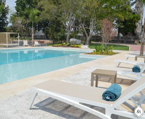 a swimming pool with two lounge chairs next to it at Rancho Macloy Hotel Spa & Social Events in Yautepec