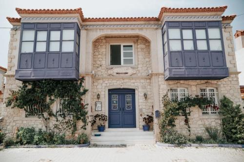 una casa con puertas y ventanas azules en Mor Salkım Konağı, en Alacati