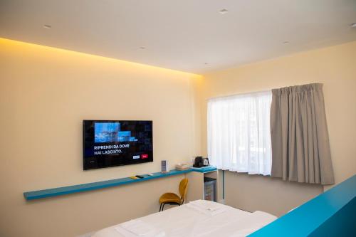 1 dormitorio con TV en la pared y 1 cama en South Hands Luxury Rooms, en Nápoles