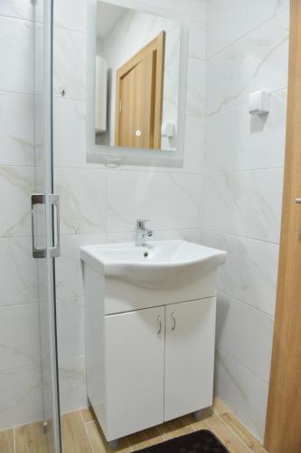 a white bathroom with a sink and a mirror at Apartmani Martenovic 1 in Vrnjačka Banja
