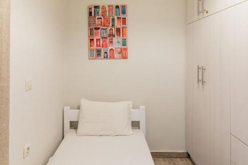 a white bedroom with a bed and a picture on the wall at Matoula's House in Nydri
