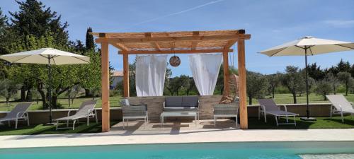 - un kiosque avec des chaises et des parasols à côté de la piscine dans l'établissement Joli Mazet Mourièsen, à Mouriès