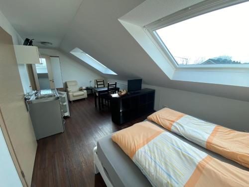 a attic room with a bed and a kitchen with a window at Pension Haselmann in Münster