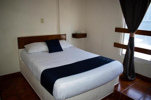 1 dormitorio con 1 cama grande con sábanas blancas y azules en Hotel Casa Blanca, en Celaya