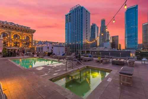 a rooftop pool with a city skyline at sunset at One Lux Stay HWH Downtown Los Angeles in Los Angeles