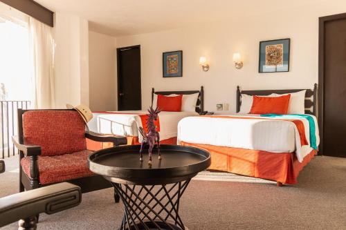 a hotel room with two beds and a chair at Hotel Victoria Oaxaca in Oaxaca City