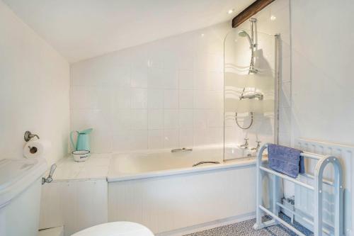 a white bathroom with a tub and a toilet at Pye Hall Cottage in Silverdale