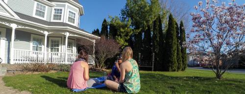 three women sitting on the grass in front of a house at Blue Skies Bed & Breakfast in Niagara on the Lake