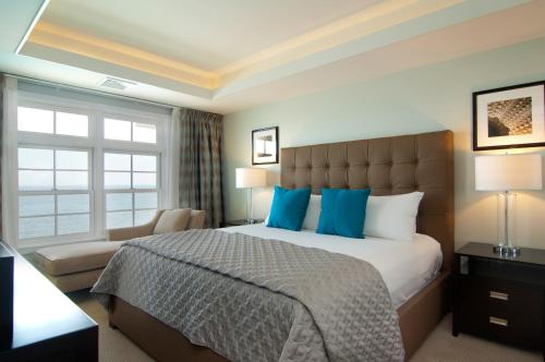a bedroom with a large bed with blue pillows at Water's Edge Resort & Spa in Westbrook