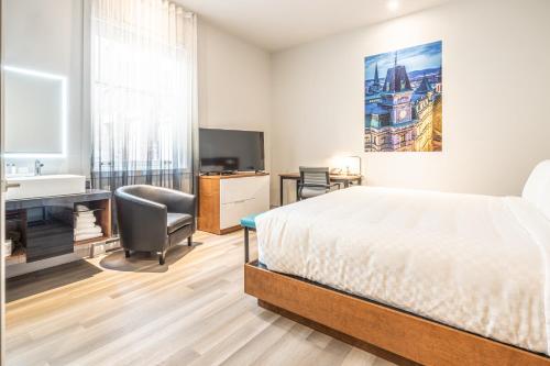 a bedroom with a bed and a desk and a television at Hôtel Manoir Vieux-Québec in Quebec City