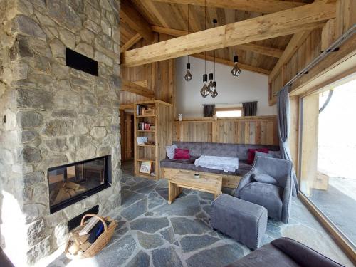 a living room with a stone fireplace and a couch at Panorama Berg Chalet in Großkirchheim