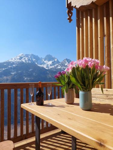 a wooden table with wine glasses and flowers on a balcony at Panorama Berg Chalet in Großkirchheim