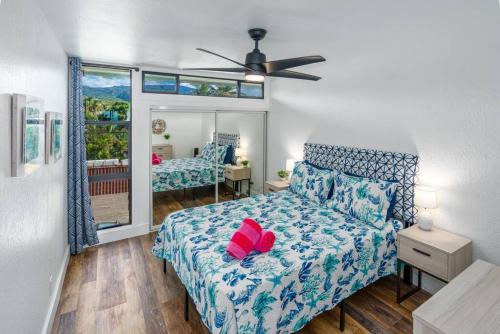 a bedroom with a bed with a red flower on it at Modern-Rustic Beach Renovation Direct Oceanfront Penthouse in Kahana