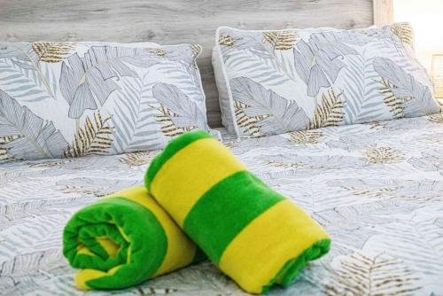 a bed with a green and yellow towel on it at Modern-Rustic Beach Renovation Direct Oceanfront Penthouse in Kahana