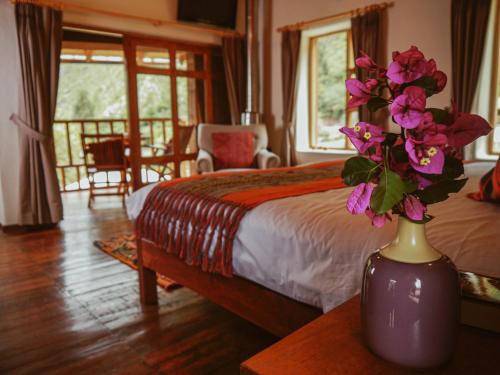 1 dormitorio con 1 cama y un jarrón con flores sobre una mesa en Unuwasi Hotel & Villa en Calca
