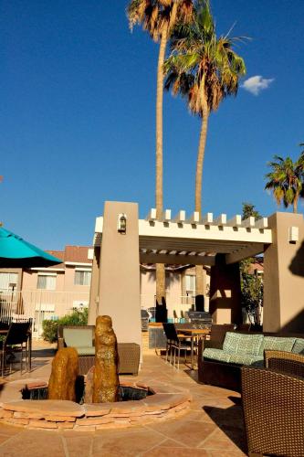 a patio with a fountain with chairs and palm trees at Sonesta ES Suites Tempe in Tempe