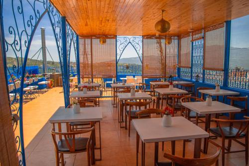 a restaurant with tables and chairs and windows at VANCII Hotel in Chefchaouene