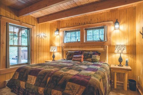 a bedroom with a bed with wooden walls and windows at Cedar Springs Cabin in Welches